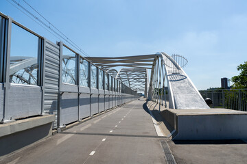 Pedestrian and bicycle footbridge along the railway bridge, connecting Grzegórzki with Zabłocie in Krakow, Poland. Train viaduct and walkway spanning over the Vistula River in Cracow, Wisła Kraków. - obrazy, fototapety, plakaty