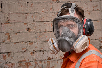Construction worker wearing full face respirator mask and ear defenders for working in hazard...