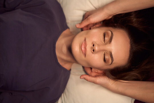 Masseuse hands massaging back of female client head