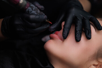Close-up in the hands of the tattoo artist, the machine in which the master introduces pigment into...