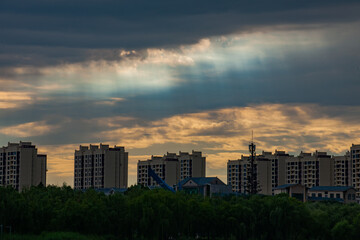 In the evening, dark clouds enveloped the sky above the city park, revealing an orange sunset scene