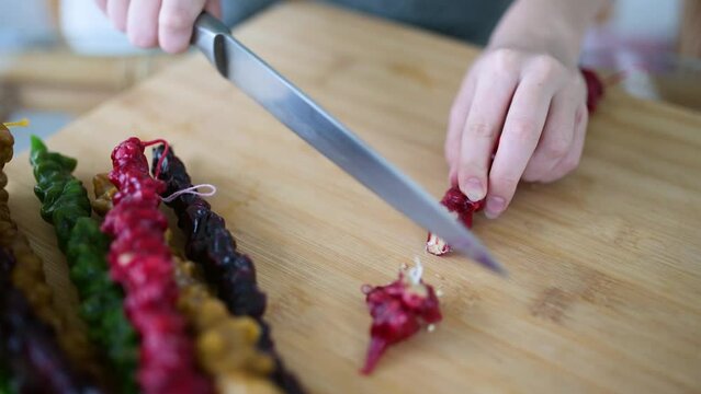 Close-up view of female hands cutting Georgian churchkhela candy into pieces