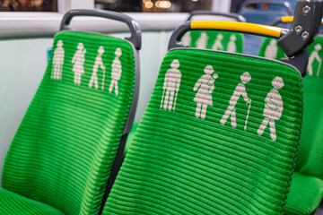 Green seats on a bus with printed signs for elderly, mother with young child, pregnant women, disabled and obese people in Dublin Docklands, Dublin, Ireland