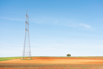 A tall pylon dominates the colorful landscape and towers above a lone tree.