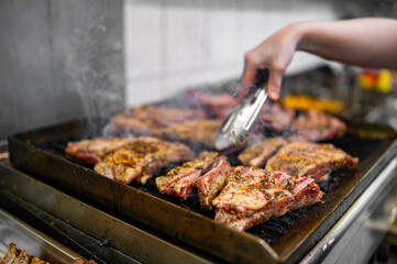 chef cooking pork ribs on grill in kitchen