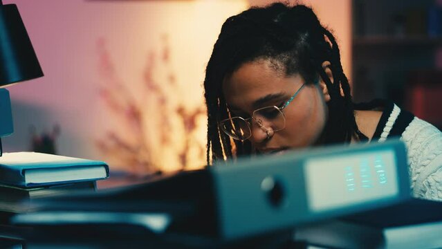 Tired African American student working on laptop late night, academic pressure