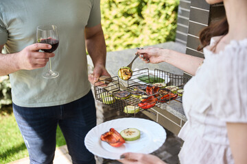 Female puts grilled vegetables on her plate