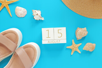 August 15 Wooden calendar on a blue background with summer accessories, top view. Vacation in...