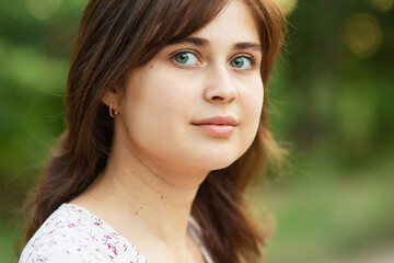 Fototapeta premium Portrait of a cute young romantic girl with brown hair in nature