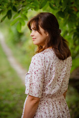 young romantic girl with brown hair near green path, woman walking on nature, natural female beauty