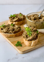 Liver pate spread on sliced ​​baguette, garnished with green onions, parsley and pretzel on a...