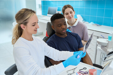 Obraz premium Smiling woman stomatologist looking at teeth x-ray of patient