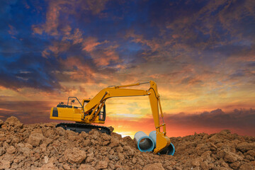 Crawler excavator is digging in the construction site pipeline work on sunset  background
