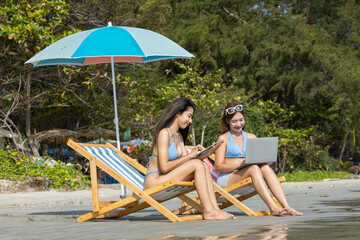 Young couple friends in summer bikini with couple listening to music enjoy playing tablet