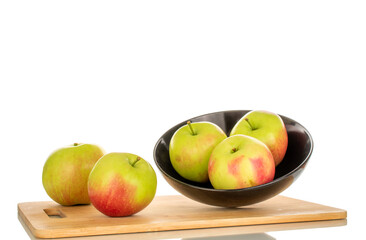 Five sweet juicy apples in a black ceramic plate and on a bamboo kitchen board, macro, isolated on white background.