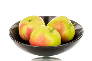 Three sweet juicy apples in a black ceramic plate, macro, isolated on white background.