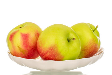 Three organic juicy apples on a light ceramic plate, macro, isolated on white background.