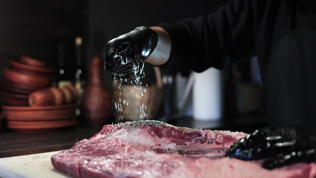 Male chef hands sprinkling salt meat piece cooking delicious food restaurant kitchen closeup slowmo