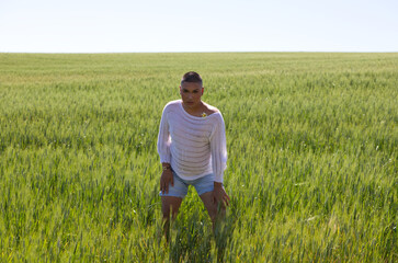 Non binary latin and young gay person has fun among the green wheat field doing different body...