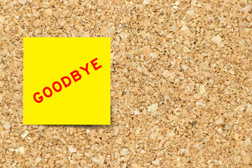 Yellow note paper with word goodbye on cork board background with copy space