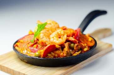 Delicious paella, cooked risotto rice with chicken thigh, king prawns, tomatoes and  chorizo - 636351997