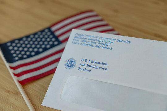 Washington, DC, USA- August, 15,2023: USCIS envelope next to the Flag of USA