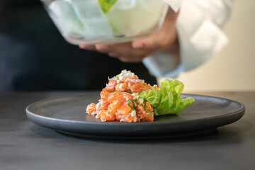 Spicy Raw Salmon Salad Thai food style decorated with Crispy fried fish skin and Yellow Flower on top and micro herb around dish. Ready to serve and eat.