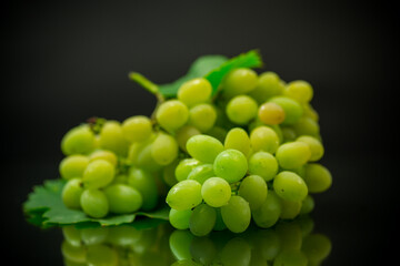 A bunch of ripe green grapes with leaves.