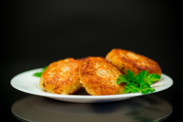 Cooked fried fish cutlets in a plate with herbs.