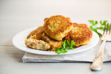 Cooked fried fish cutlets in a plate with herbs.