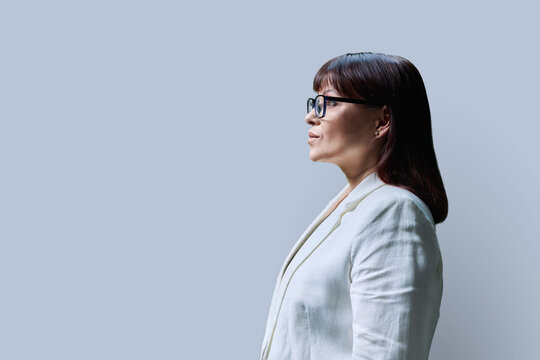 Serious mature business woman, profile view on grey studio background