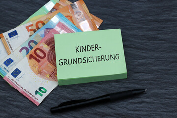 Notizblock mit dem Text Kindergrundsicherung auf Euro Geldscheinen.