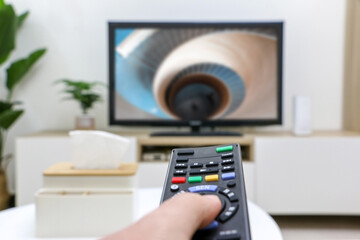 Watching and streaming TV and movies, first-person perspective, holding remote control, TV screen burred in background. Nice and relaxed in modern living room interior
