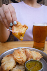 Eating fried food. Closeup view of a woman having a pint of beer and dipping a fried chicken snack in mustard.	
