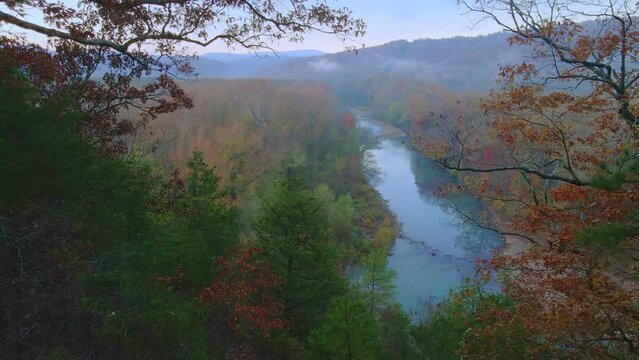Drone arial view of autumn river in the ozark mountains of Arkansas with fall colored forest during early morning  