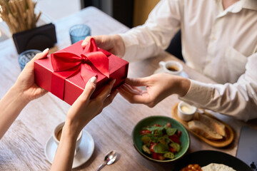 Top view woman making present to her man giving cute red gift box