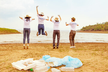 Back view volunteer groups men and women run and jump in the sky celebrating achievements achieving goals recreational activities garbage collection cleaning on the beach natural attractions.