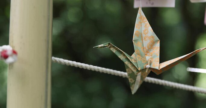 A paper crane swaying in the wind at the traditional street close up handheld