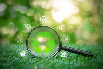 Magnifying glass focused on Recycle symbol on the grass in garden with green nature background for...