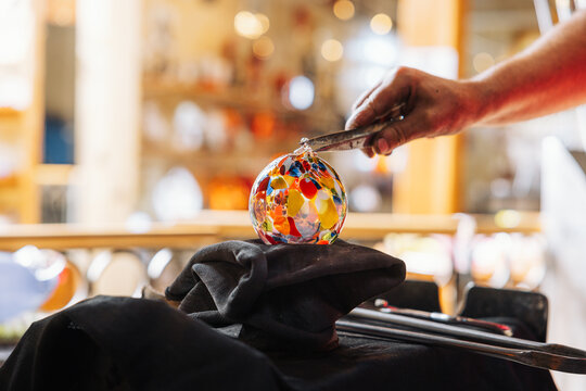 Glassblower crafting a Christmas bauble, from the heat of the oven to shaping it. Workshop based in France.