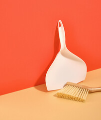 A white dustpan and hand brush stands on the table. Space for text. Household routine. - obrazy, fototapety, plakaty