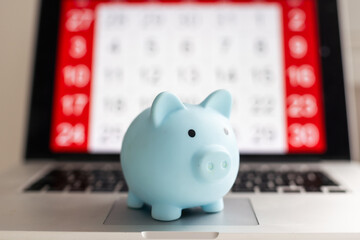 White piggy bank on monthly calendar year 2020 on white background, from top view. Concept for money saving plan, financial accounting, or new year resolution