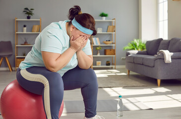 Portrait of a funny young fat overweight woman tired after fit sport exercises covering face with...