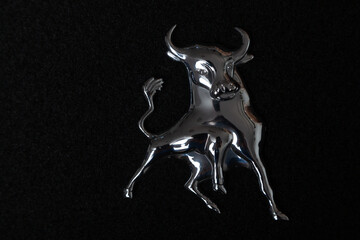 Metal figure of bull on black background..