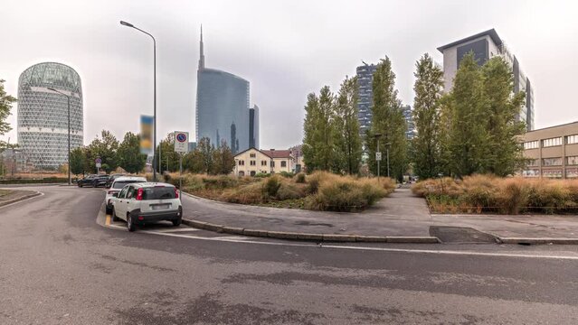 Panorama showing skyscrapers and towers from park with outumn treea and green lawn timelapse. Located between Piazza Gae Aulenti and the Isola district. Traffic on a road. Milan. Italy