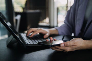 Asian Business woman using calculator and laptop for doing math finance on an office desk, tax, report, accounting, statistics, and analytical research concept