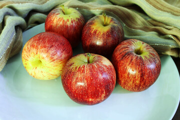 Apples in a white plate. Fruits on the fabric.