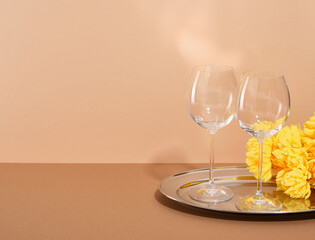 Two empty glasses on a round tray and yellow flowers. Copy space for text. Love relationship celebration concept.