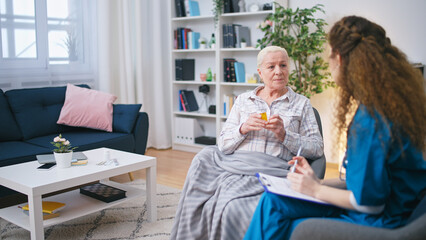 A woman general practitioner explains the dosage of medication to a senior female patient