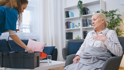 Emergency nurse taking equipment from her medical kit to give first aid to a senior woman